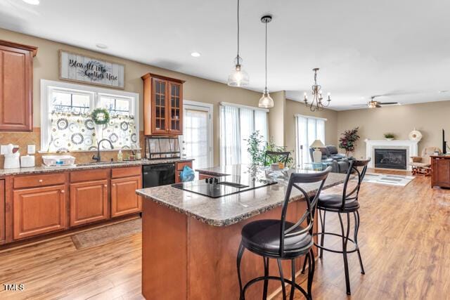 kitchen featuring black appliances, stone countertops, a kitchen bar, and a sink