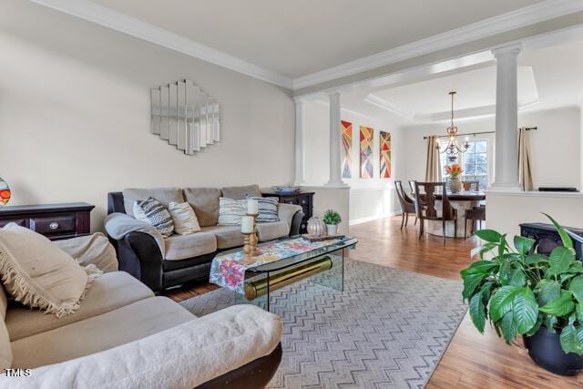 living room featuring crown molding, wood finished floors, and ornate columns