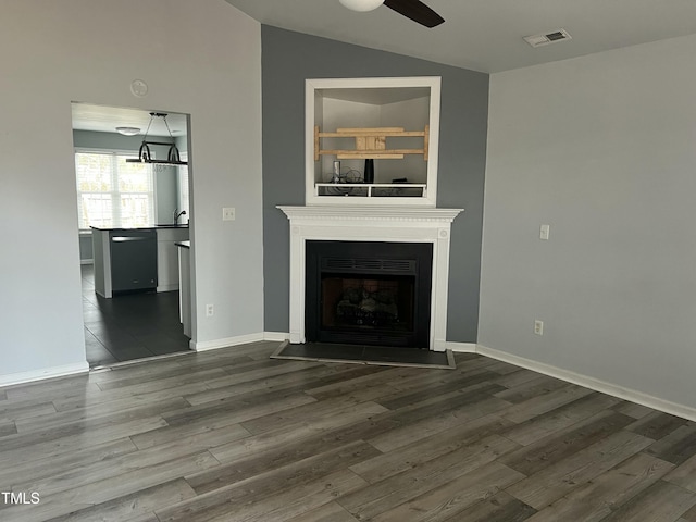 unfurnished living room with a fireplace with flush hearth, visible vents, vaulted ceiling, and dark wood-type flooring