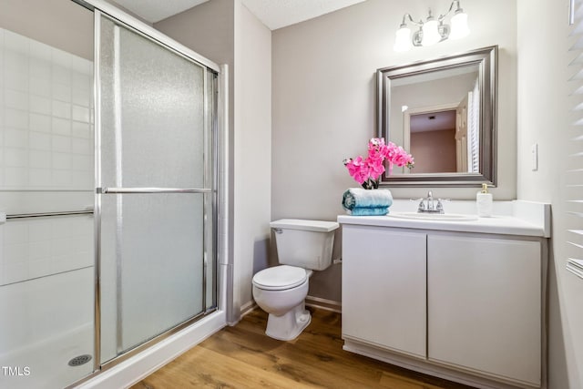 full bathroom featuring a stall shower, vanity, toilet, and wood finished floors