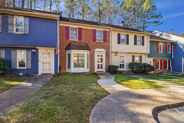 multi unit property featuring brick siding and a front lawn