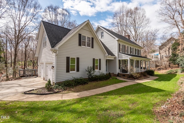 view of front of home featuring a porch, an attached garage, concrete driveway, a chimney, and a front yard