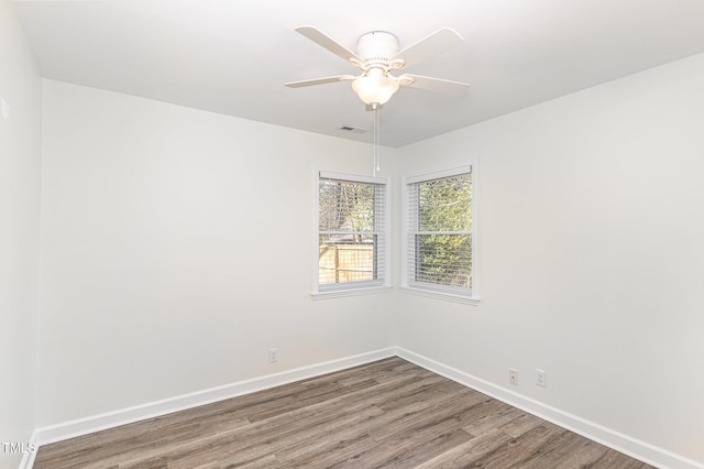 empty room with ceiling fan, visible vents, baseboards, and wood finished floors