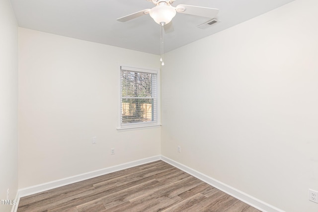 spare room with visible vents, ceiling fan, baseboards, and wood finished floors