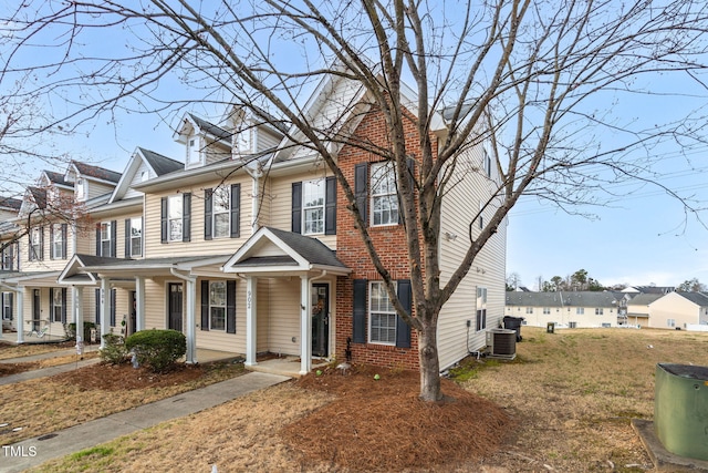 view of property with central AC unit, a residential view, a porch, a front lawn, and brick siding