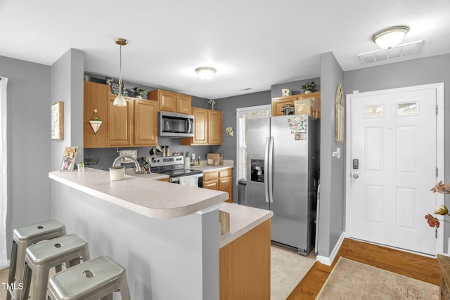 kitchen with visible vents, a kitchen breakfast bar, a peninsula, stainless steel appliances, and light countertops