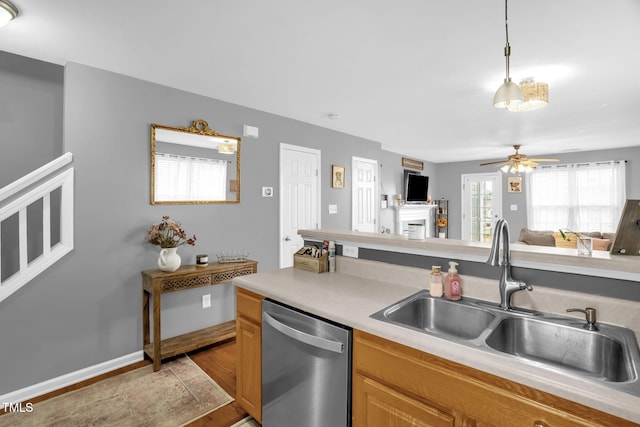 kitchen featuring open floor plan, light countertops, a sink, and stainless steel dishwasher