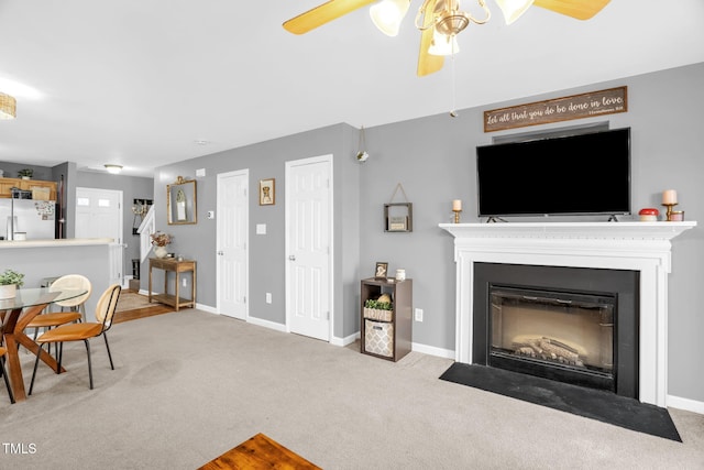 carpeted living area featuring a fireplace with flush hearth, ceiling fan, and baseboards