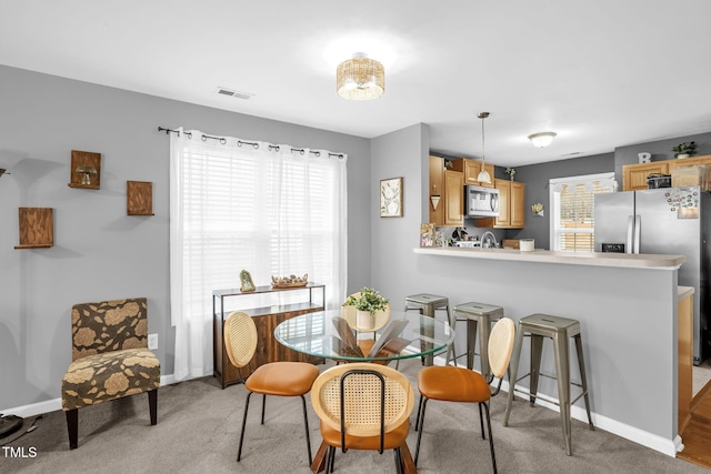 dining area featuring visible vents, plenty of natural light, light carpet, and baseboards