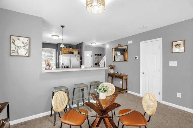 carpeted dining area featuring stairway and baseboards