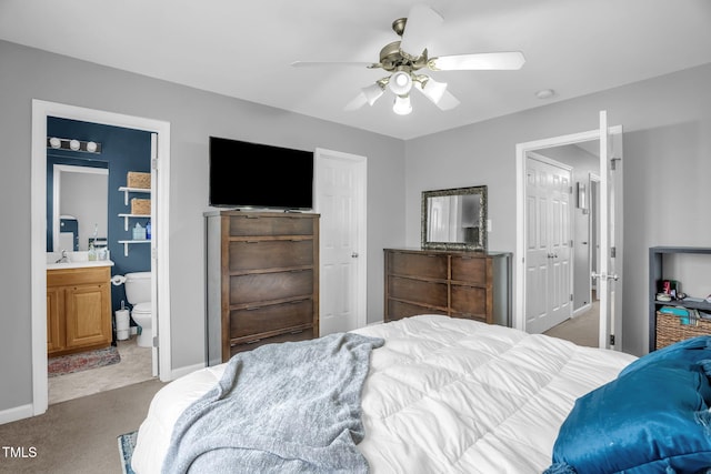 bedroom featuring carpet, a ceiling fan, a sink, ensuite bath, and baseboards