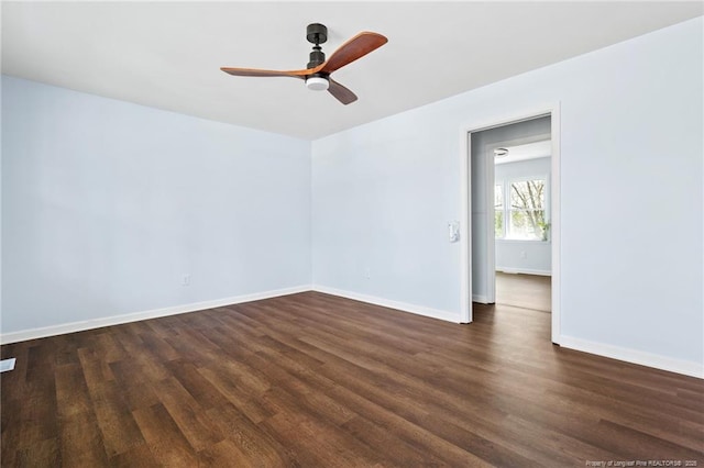 unfurnished room featuring baseboards, dark wood finished floors, and a ceiling fan