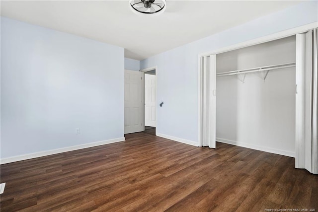 unfurnished bedroom featuring a closet, dark wood-style flooring, and baseboards