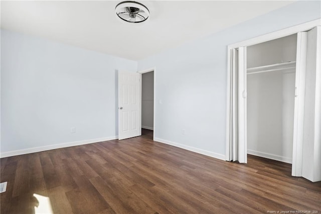 unfurnished bedroom with baseboards, dark wood finished floors, and a closet