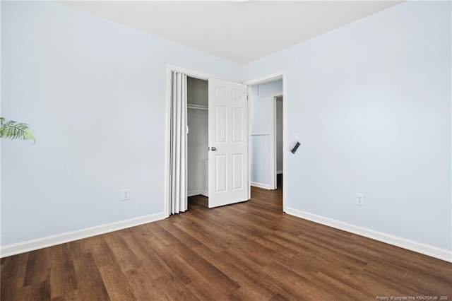 unfurnished bedroom featuring dark wood-style floors, a closet, and baseboards