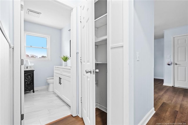 bathroom featuring baseboards, visible vents, toilet, wood finished floors, and vanity