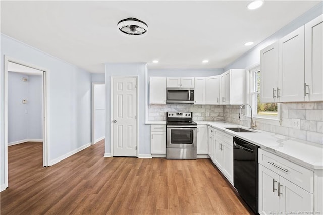 kitchen featuring backsplash, stainless steel appliances, a sink, and light wood finished floors