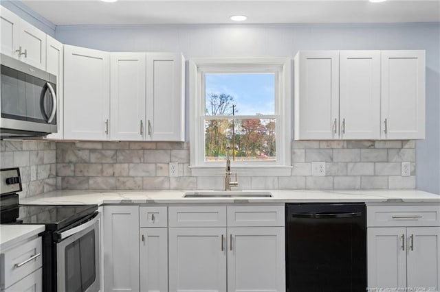 kitchen with appliances with stainless steel finishes, white cabinetry, a sink, and backsplash