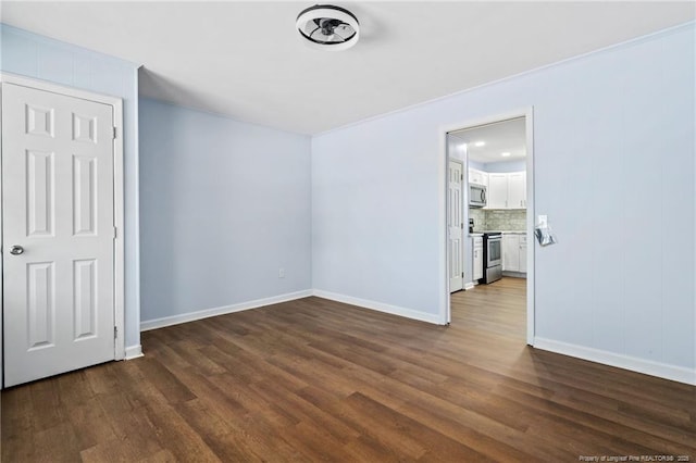 empty room with dark wood-style flooring and baseboards