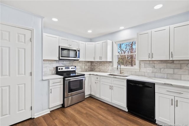 kitchen with light stone countertops, dark wood-style floors, a sink, white cabinets, and appliances with stainless steel finishes