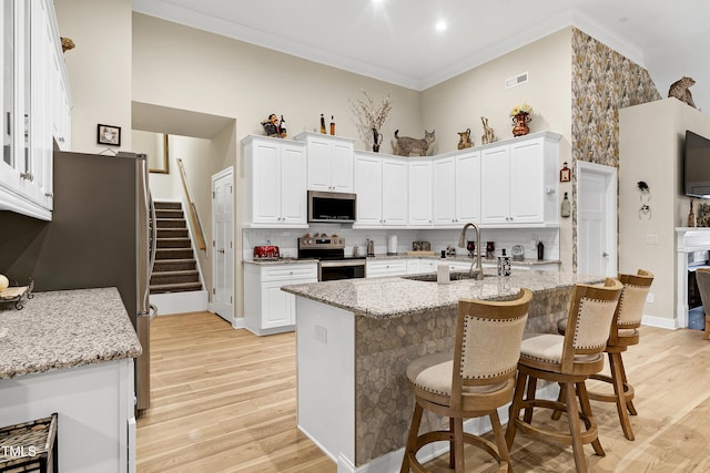 kitchen with visible vents, a sink, light wood-style floors, appliances with stainless steel finishes, and crown molding