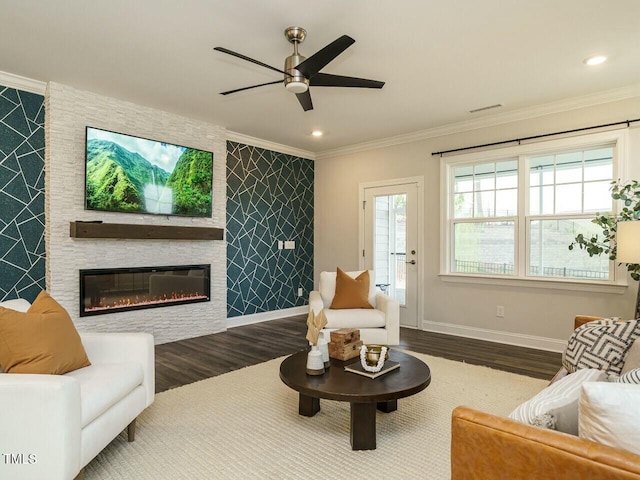 living area with baseboards, a fireplace, wood finished floors, and crown molding