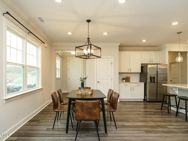 dining area featuring an inviting chandelier, dark wood-style floors, visible vents, and ornamental molding