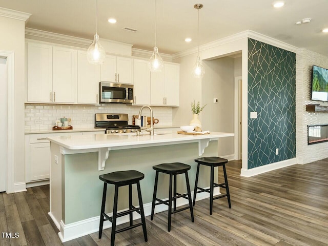 kitchen featuring a sink, stainless steel appliances, dark wood-type flooring, white cabinets, and light countertops