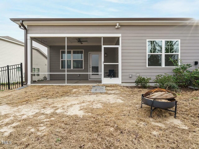 back of property featuring fence, ceiling fan, an outdoor fire pit, and a sunroom