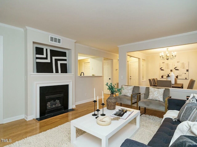 living room with visible vents, baseboards, a notable chandelier, and wood finished floors