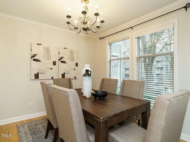 dining area with a notable chandelier, light wood-style floors, baseboards, and ornamental molding