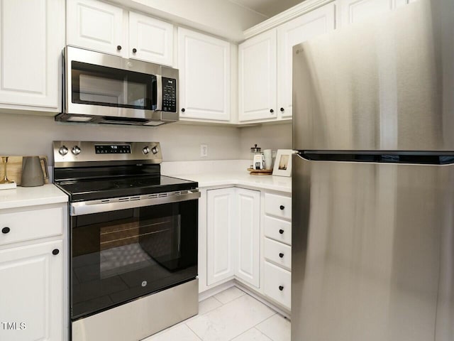 kitchen with light countertops, white cabinets, marble finish floor, and stainless steel appliances