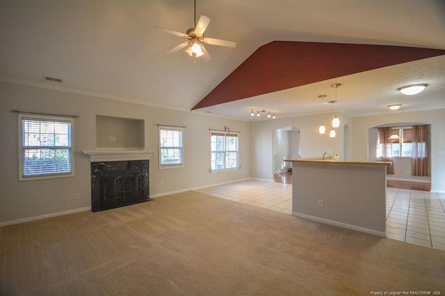 unfurnished living room featuring a healthy amount of sunlight, light tile patterned floors, a premium fireplace, and light colored carpet