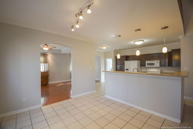 kitchen featuring arched walkways, light tile patterned floors, white appliances, dark brown cabinets, and crown molding