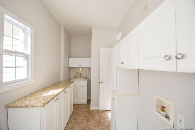 washroom with hookup for a washing machine, cabinet space, a sink, and visible vents