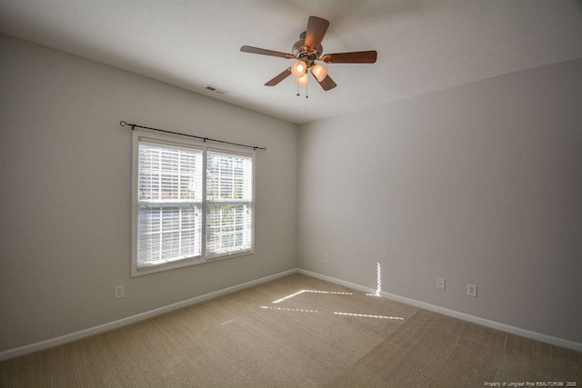 carpeted empty room featuring visible vents, baseboards, and ceiling fan