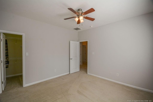 unfurnished bedroom featuring light carpet, baseboards, visible vents, and a walk in closet