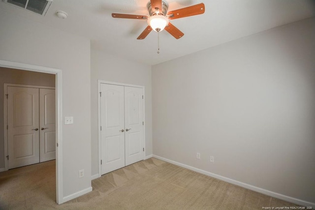 unfurnished bedroom featuring light carpet, a closet, visible vents, and baseboards