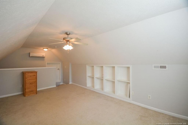 bonus room with visible vents, ceiling fan, a wall mounted air conditioner, vaulted ceiling, and a textured ceiling