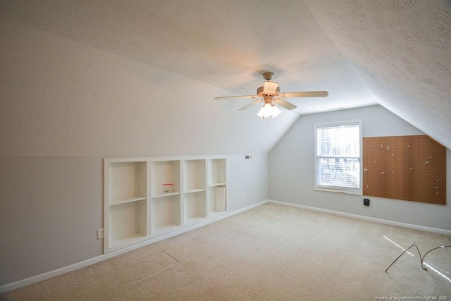 additional living space with vaulted ceiling, a textured ceiling, and carpet flooring