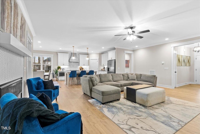 living room with recessed lighting, crown molding, and light wood finished floors