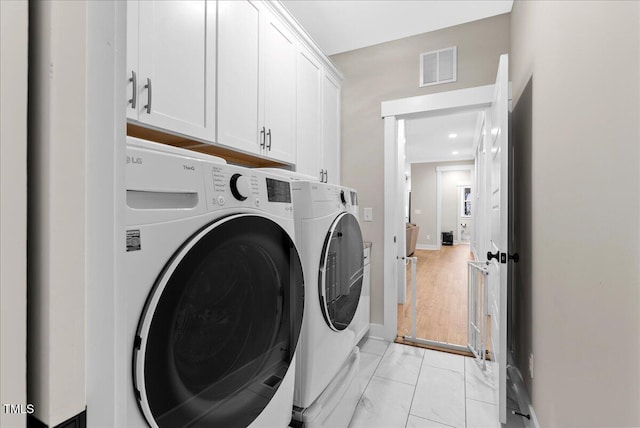 laundry area featuring cabinet space, washing machine and dryer, visible vents, and baseboards