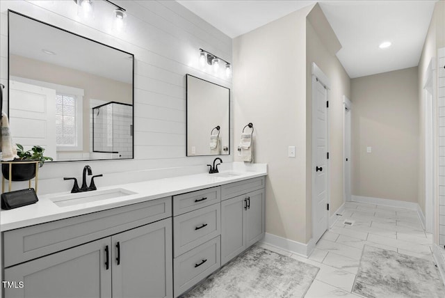 bathroom featuring marble finish floor, baseboards, a sink, and a stall shower