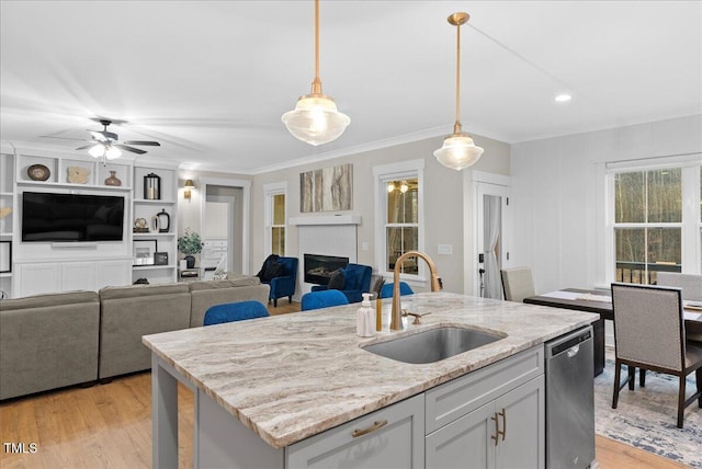 kitchen with dishwasher, light wood finished floors, a fireplace, and a sink