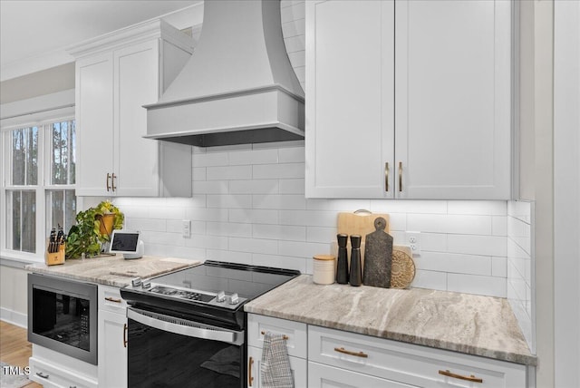 kitchen featuring white cabinets, backsplash, built in microwave, electric range oven, and custom range hood