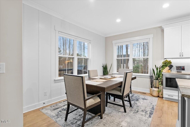 dining space featuring light wood-style floors, recessed lighting, crown molding, and baseboards