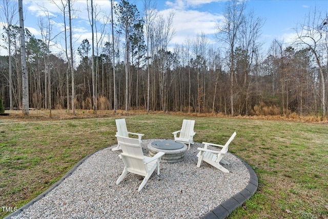 view of yard featuring an outdoor fire pit and a wooded view