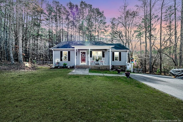 view of front of home with a porch, a lawn, and driveway