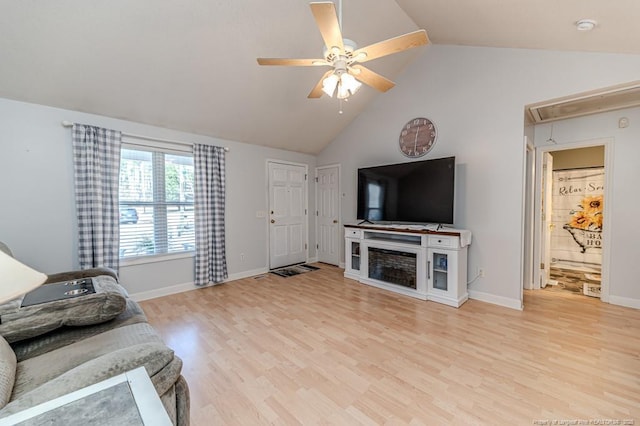 living room with attic access, a ceiling fan, vaulted ceiling, and wood finished floors