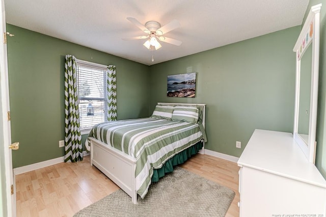 bedroom with ceiling fan, light wood finished floors, a textured ceiling, and baseboards